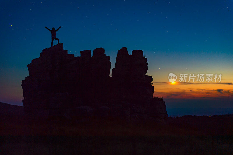 Hikers stand at the top of the mountain to watch the moon set